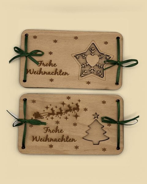 Zwei Geldgeschenke aus Holz zu Weihnachten: eins mit Stern-Fenster, eins mit Tannenbaum-Fenster und Rentierschlitten, beide mit grüner Schleife